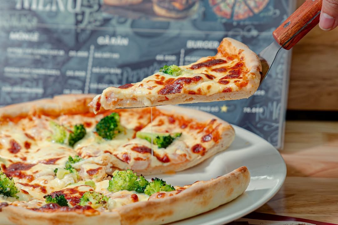 Xúc miếng pizza bông cải xanh phô mai kéo sợi tại The Symphony's Pizza